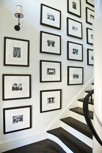 Kaufman Residence, decorated by Phoebe Howard, framed christmas card pictures on stairs-----
Over a dozen black-and-white framed Christmas cards are hanging on wall over staircase.
